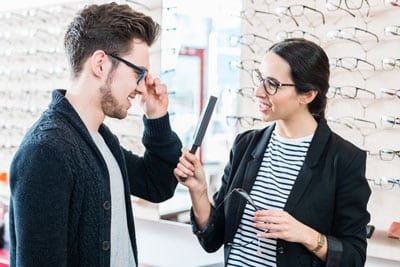 opticienne en train de faire essayer des lunettes à un client - ICO ecole optique Paris sud